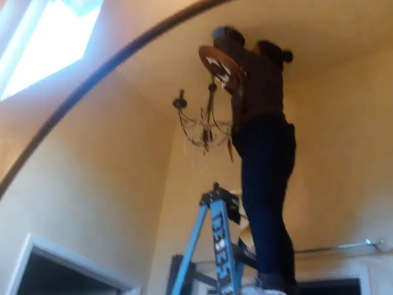 Electrician installing a chandelier in a Torrance residence